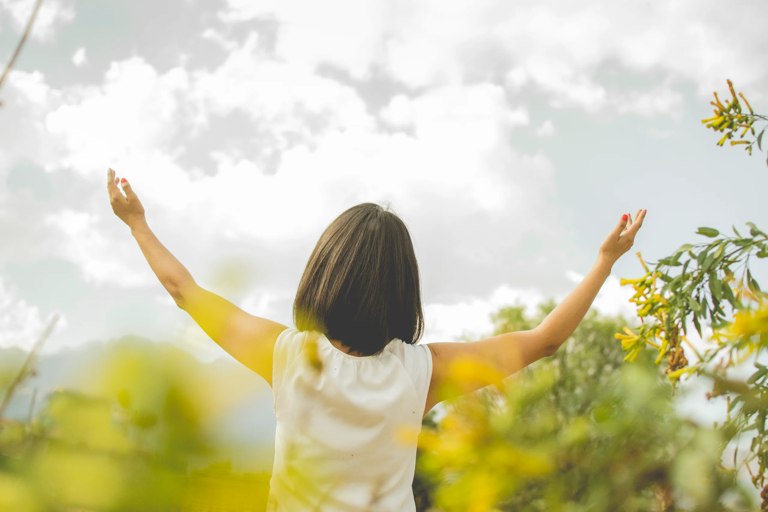 A woman standing in nature with her arms open